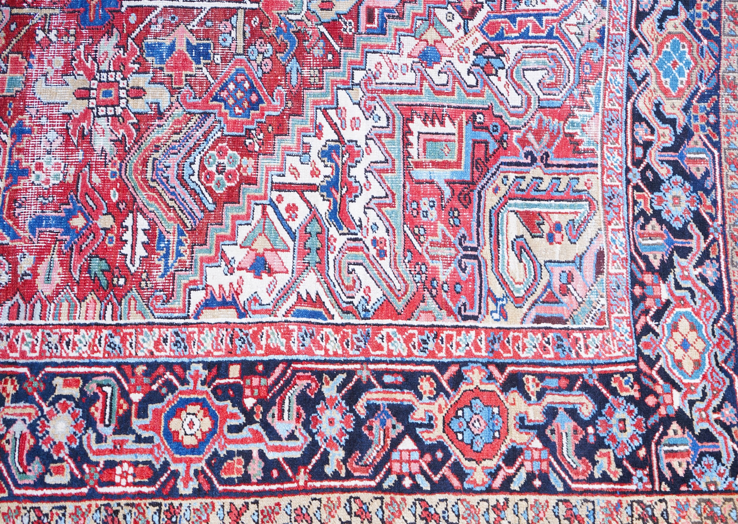 An antique Heriz brick red ground carpet with central